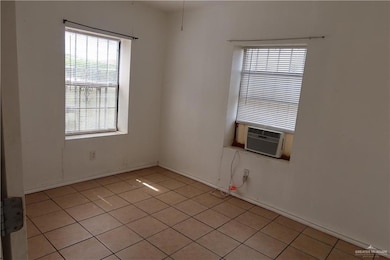 Spare room with light tile patterned floors, baseboards, and cooling unit