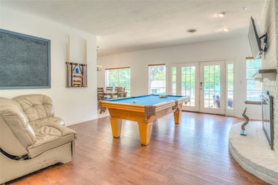Game room with hardwood / wood-style flooring, french doors, billiards table, and a brick fireplace