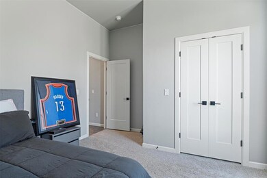 Carpeted bedroom with high vaulted ceiling and a c