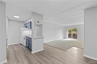 Kitchen featuring a textured ceiling, white appliances, visible vents, blue cabinetry, and light wood-type flooring