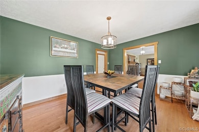 Dining room with a chandelier, light hardwood / wood-style floors, and a textured ceiling