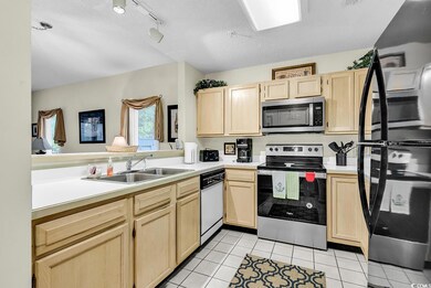 Kitchen featuring stainless steel appliances, light brown cabinetry, light tile patterned floors, light countertops, and a textured ceiling