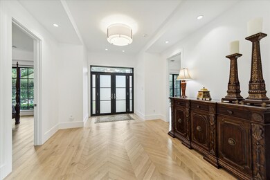 Elegant entryway with striking steel-framed doors and herringbone wood flooring.