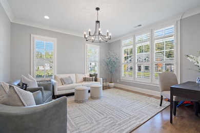 Living room with wood finished floors, ornamental molding, a chandelier, and recessed lighting
