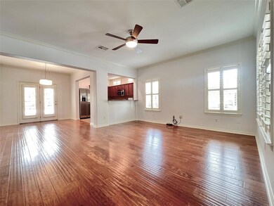 Unfurnished living room with a ceiling fan, ornamental molding, and wood finished floors