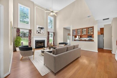 Living room featuring light wood-type flooring, a high ceiling, healthy amount of natural light, a fireplace with flush hearth, and ceiling fan