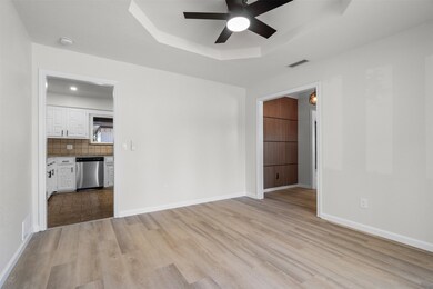 Empty room featuring a tray ceiling, light wood-type flooring, and a ceiling fan