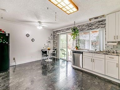 Kitchen with white cabinets, a textured ceiling, stainless steel dishwasher, a ceiling fan, and light stone countertops