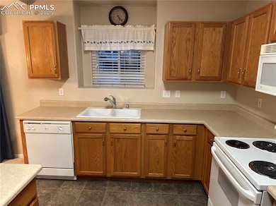 Kitchen with white appliances, light countertops, and brown cabinetry
