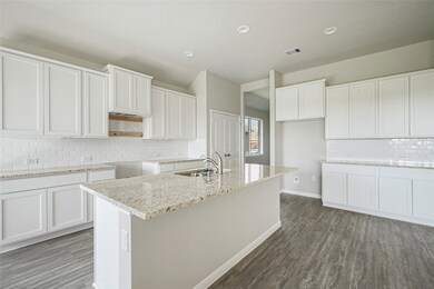 The kitchen features gorgeous custom cabinetry, an extended Island for an eat-in space, gorgeous wood-like flooring and an elegant backsplash and recessed canned lighting.