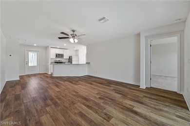 Unfurnished living room featuring dark hardwood /