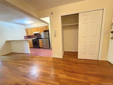 Kitchen featuring tasteful backsplash, stainless steel appliances, light wood-style floors, light countertops, and under cabinet range hood
