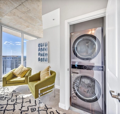 Washroom featuring a wall of windows, stacked washer and clothes dryer, and carpet