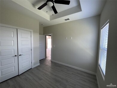Unfurnished bedroom with multiple windows, a tray ceiling, and dark wood-type flooring