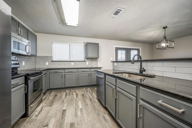 Kitchen featuring gray cabinets, appliances with stainless steel finishes, sink, and a wealth of natural light