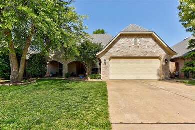 View of front facade with a garage, a front yard, driveway, brick siding, and stone siding