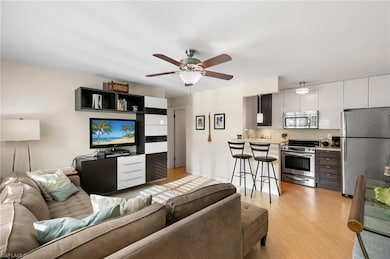 Living room with ceiling fan and light hardwood / 
