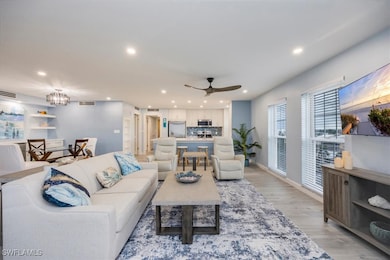 Living room featuring light wood-style flooring, recessed lighting, ceiling fan, and a chandelier