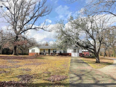 Single story home featuring covered porch, gravel driveway, and brick siding.