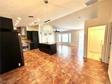 Kitchen with dark cabinetry, a sink, visible vents