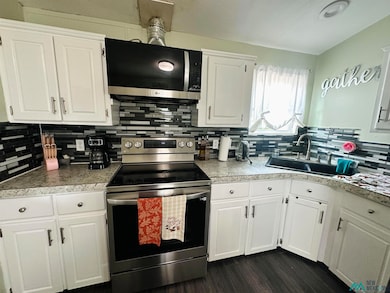 Kitchen with appliances with stainless steel finishes, white cabinets, tasteful backsplash, light countertops, and dark wood finished floors
