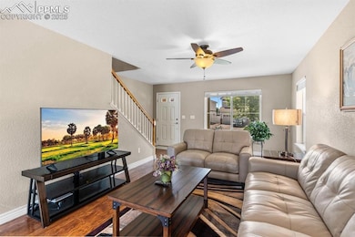 Living room featuring stairway, ceiling fan, a textured wall, baseboards, and wood finished floors