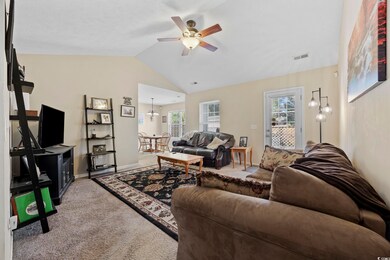 Living area featuring lofted ceiling, carpet floors, a ceiling fan, and a chandelier