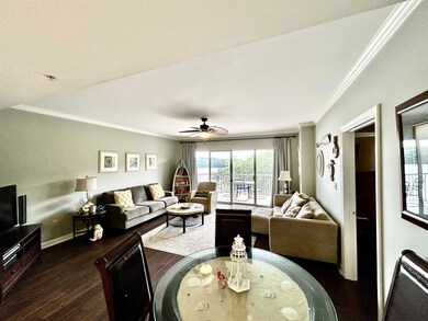 Living room featuring dark wood-style flooring, ornamental molding, ceiling fan, and baseboards