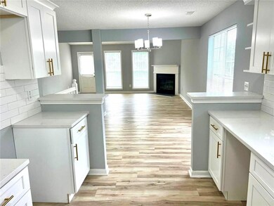 Kitchen with light countertops, a textured ceiling, decorative backsplash, light wood-type flooring, and white cabinetry