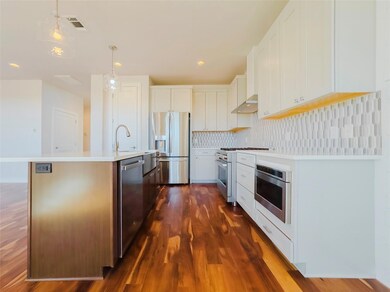 Kitchen with appliances with stainless steel finishes, white cabinets, decorative backsplash, a kitchen island with sink, and dark wood-type flooring