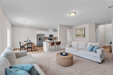 Living area featuring baseboards, light carpet, vi