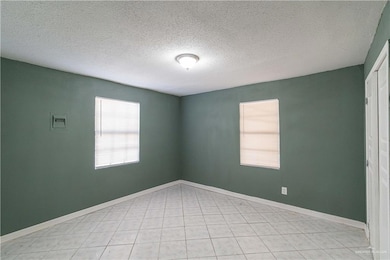 Empty room with baseboards and a textured ceiling
