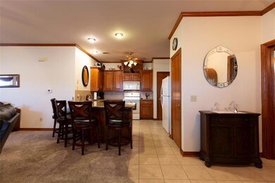Kitchen featuring ornamental molding, brown cabinetry, a peninsula, white appliances, and a breakfast bar