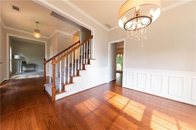 Foyer featuring a notable chandelier, stairs, wood