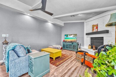 Living area with a textured wall, wood finished floors, a textured ceiling, beamed ceiling, and a fireplace