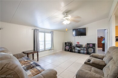 Tiled living room with ceiling fan, crown molding,