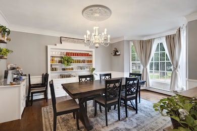 Dining area with a chandelier, ornamental molding, wood finished floors, and a baseboard radiator