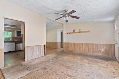 Unfurnished room featuring ceiling fan, wainscotin