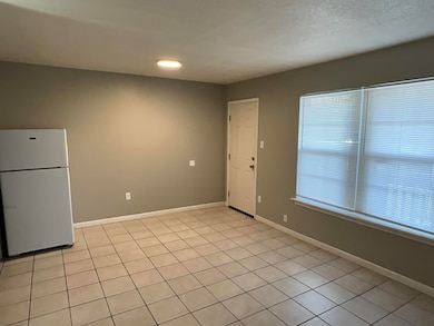 Spare room featuring baseboards, a textured ceiling, and a healthy amount of sunlight