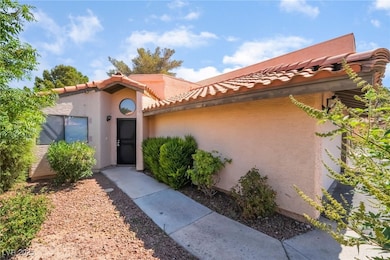 View of exterior entry with a tile roof and stucco
