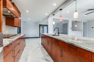 Kitchen with brown cabinetry, light stone countertops, decorative light fixtures, recessed lighting, and decorative backsplash