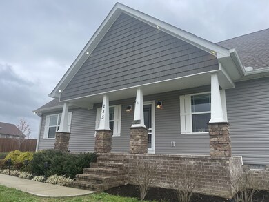 The covered front porch features stacked stone columns and beautiful landscaping leading to the front door.