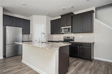 Kitchen featuring appliances with stainless steel finishes, a sink, dark wood-type flooring, and tasteful backsplash