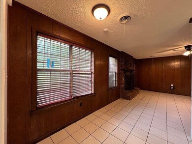 Empty room with wood walls, a fireplace, ceiling f