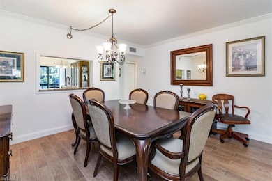 Dining area featuring tile with wood-style floors, ornamental molding, and a notable chandelier