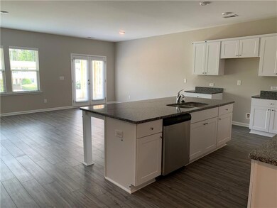 Kitchen featuring stainless steel dishwasher, dark wood-style floors, a center island with sink, white cabinets, and recessed lighting