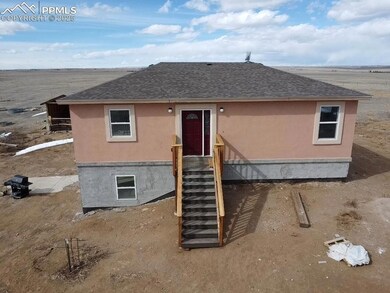 Back of house featuring stucco siding and roof with shingles