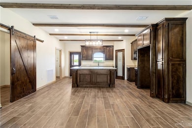 Kitchen featuring visible vents, a barn door, dark brown cabinetry, and wood tiled floor