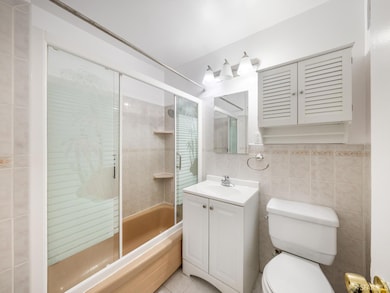 Full bathroom with combined bath / shower with glass door, vanity, tile walls, and tile patterned flooring