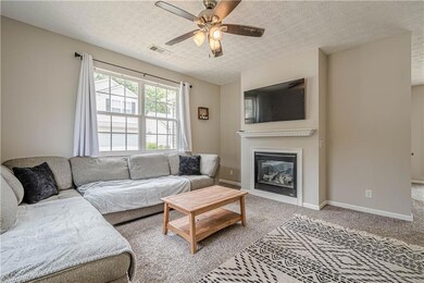 Carpeted living area featuring ceiling fan, a glas